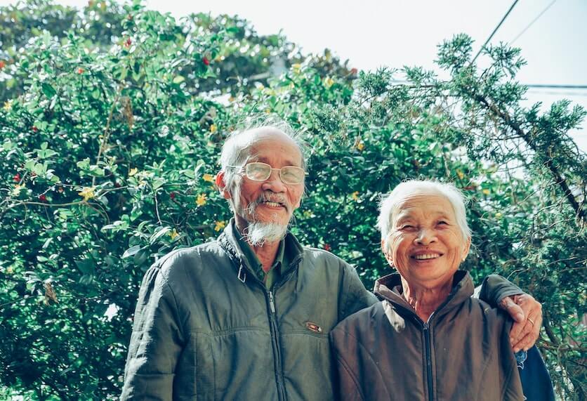 An Older Man and Woman Smiling Together in front of a Tree