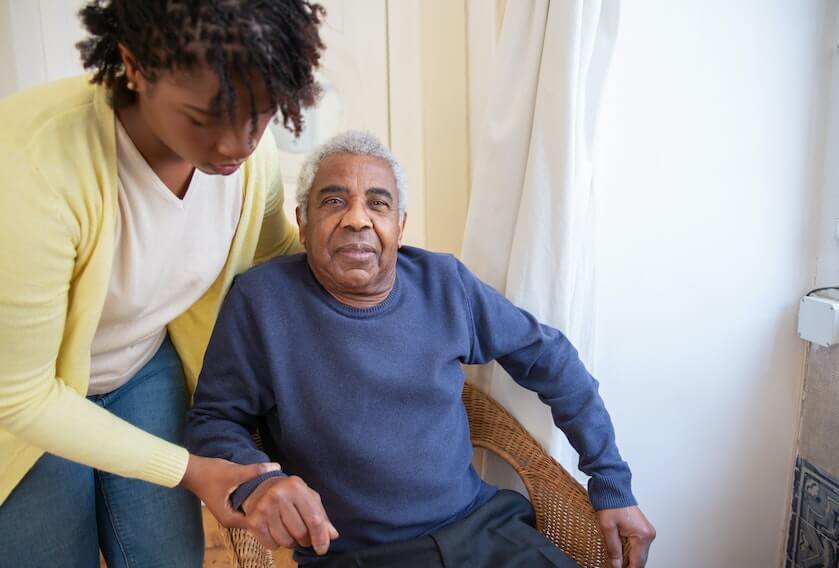 Caregiver Helping a Senior Man Get up from a Chair
