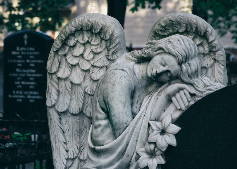 How Does Burial Insurance Work and Angel Near Tombstone in a Graveyard