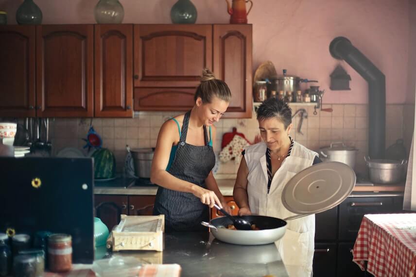 Lady Helping a Senior With Cooking