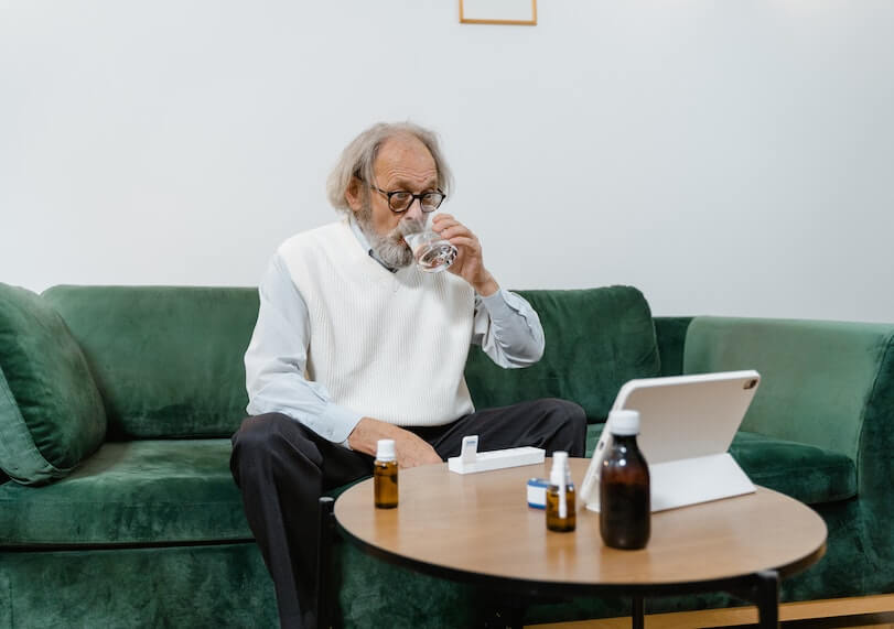 Senior Man Drinking Water and Anitbiotics