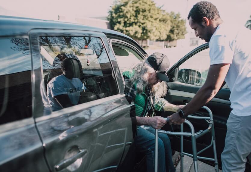 Young Man Helping an Elder Man Get Out of a Car